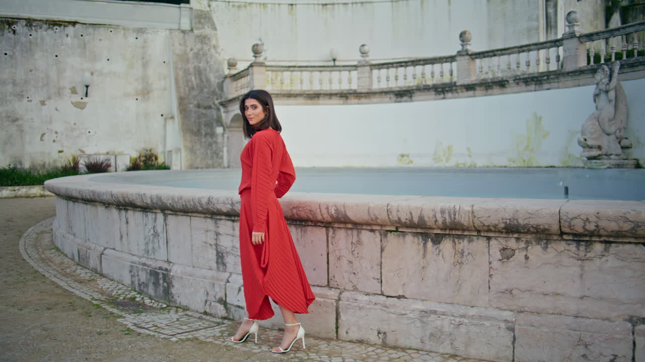 Sensual woman walking fountain square posing. Model touching concrete border