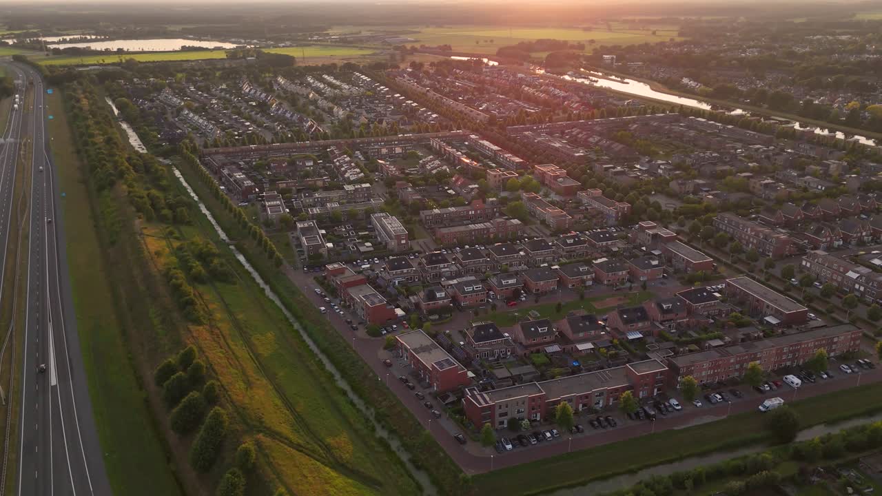 Aerial view of a suburban residential area with a highway and landscape at sunset