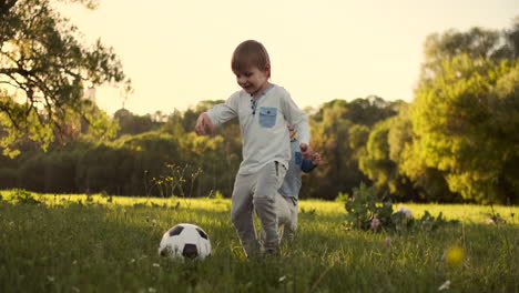 in slow motion a happy boy with a soccer ball runs into the field at sunset dreaming of playing professional football.
