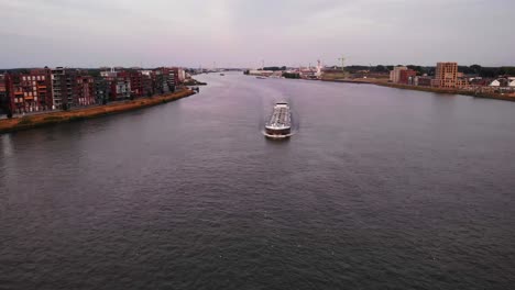 empty container ship cruises through dordrecht, on river