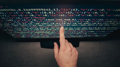 mano apuntando a un código en una pantalla de computadora