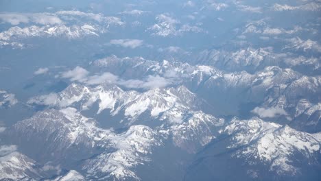 high up scenic airplane view of snow capped mountains on a sunny day