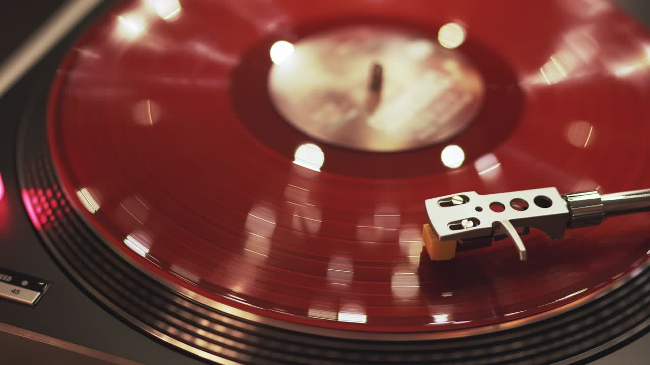 비닐 플레이어: 해가 지는 배경, 보케 조명, 저녁 도시, 소녀의 손이 바늘을 놓고 회전하는 빨간 비닐 판, 그라모폰 회전 판, 크리스마스 조명, 인기 있는 디스코 트렌드, 70년대, 80년대, 90년대