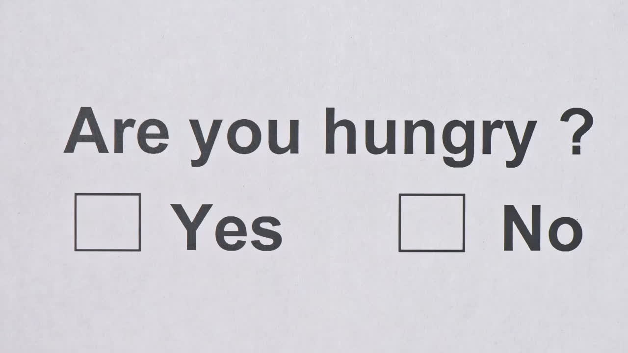 Overhead shot of a caucasian man answering to the question: Are you hungry? on the white piece of sheets