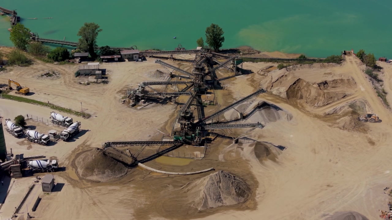 Gravel quarry combined with concrete production hub. Mixer trucks waiting for loading in large industrial construction materials facility.