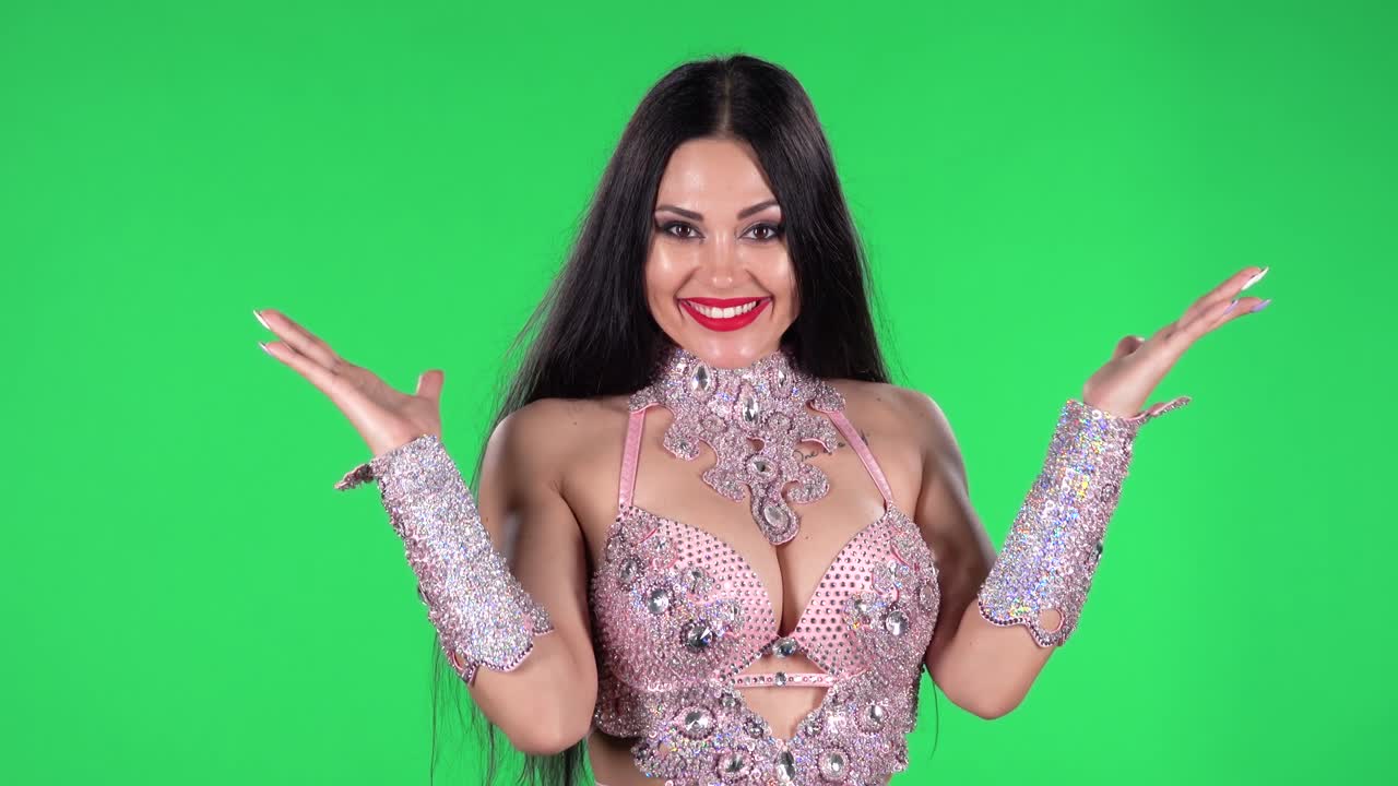 retrato de uma mulher bonita em um vestido chique para danças orientais em pedras e pedras está olhando direito com expressões faciais chocadas e surpreendidas. ecrã verde