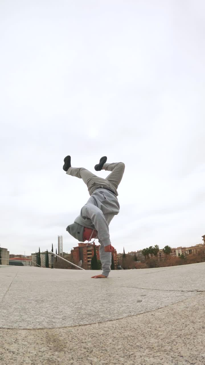Breakdancer performing handstand freeze in urban environment