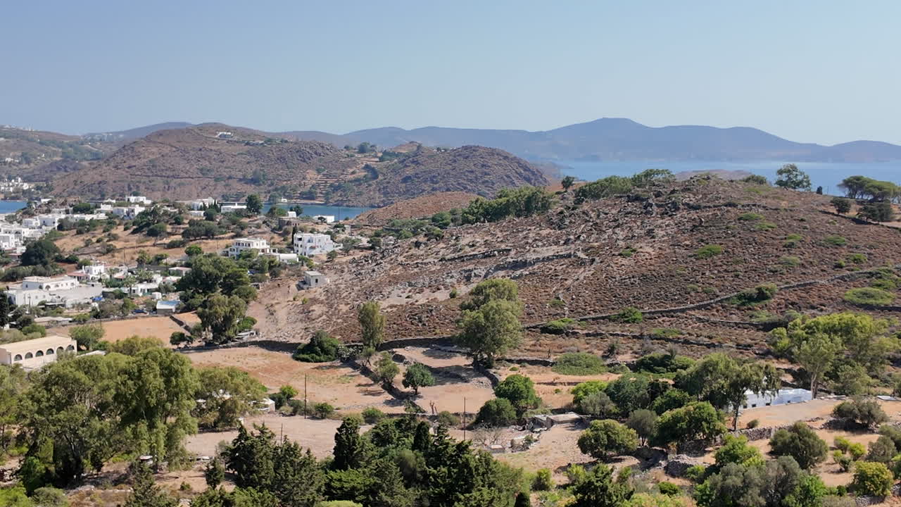 Greece,Patmos Island,Scala town view from the hill top,hills full with pine and olive trees,traditional white houses and the Scala Bay. Picturesque island with beautiful landscapes and buildings.