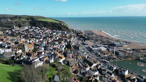 tomada aérea de un dron de hastings, reino unido, tomada en órbita, volando sobre la ciudad vieja mirando hacia la ciudad, el océano y east hill