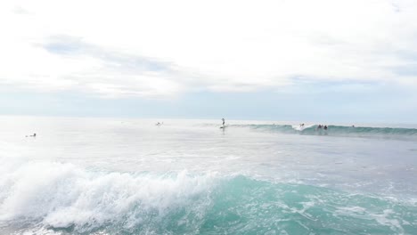 drone flying up and over surfers in the ocean in sri lanka