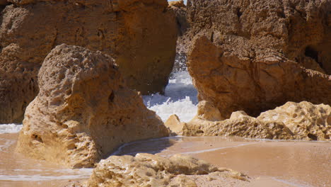 waves at the red rock cliffs of praia do evaristo beach in algarve portugal