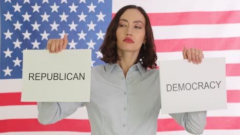 woman holds signs for 'republican' and 'democracy' against an american flag