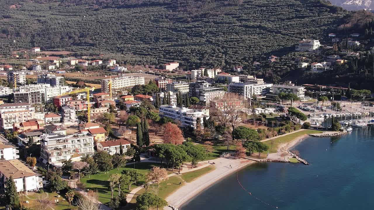 Montagne che circondano una piccola città vicino a un lago in Italia durante le ore diurne