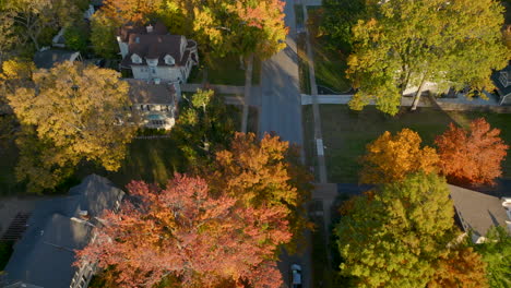 Aerial-flying-over-a-street-in-Kirkwood-on-a-gorgeous-Fall-day-at-peak-color-with-cars-going-up-and-down-the-street