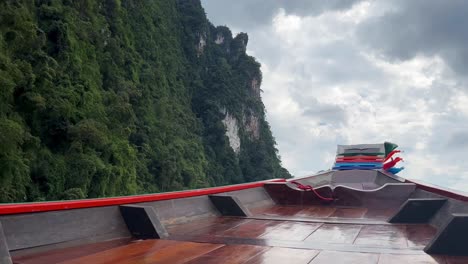 the front view of a long-tail boat gliding through the waters of a lake