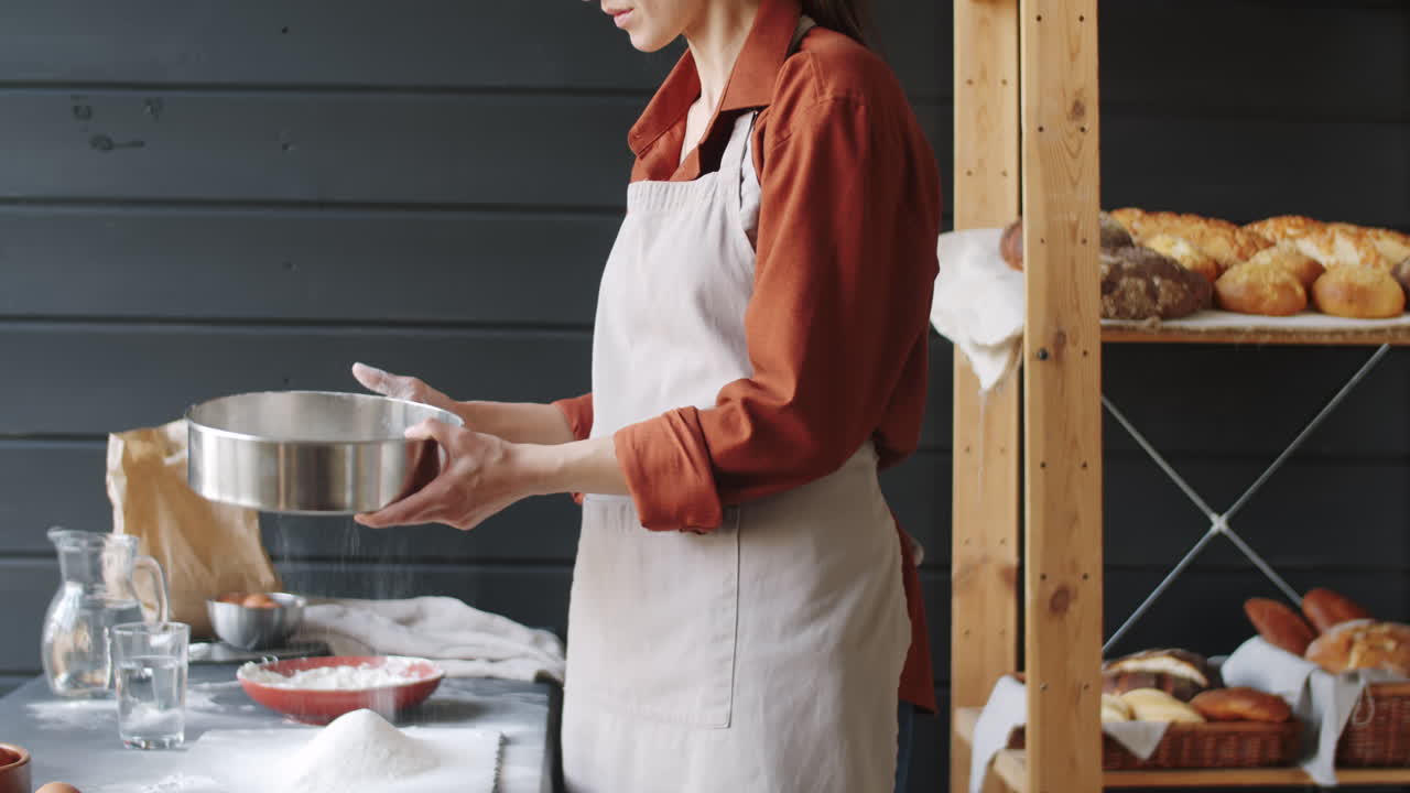 trabajadora de panadería filtrando harina en la cocina