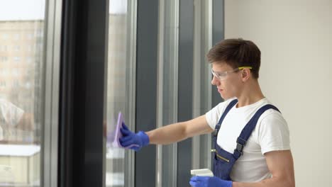 young cleaner in protective uniform washes windows