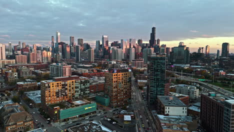 aerial view backwards over the sunlit cityscape of river west, fall sunset in chicago