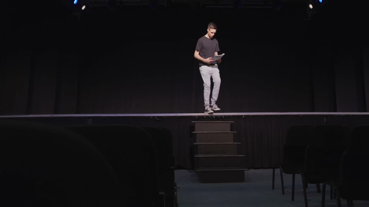 adolescente caucásico en el auditorio de la escuela secundaria preparándose para una actuación