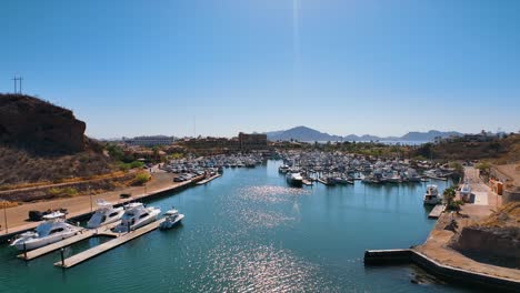 toma aérea de drones entrando en un puerto deportivo lleno de barcos y veleros en un puerto cálido