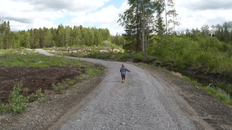 ragazzo del bambino che corre su strada sterrata deserta