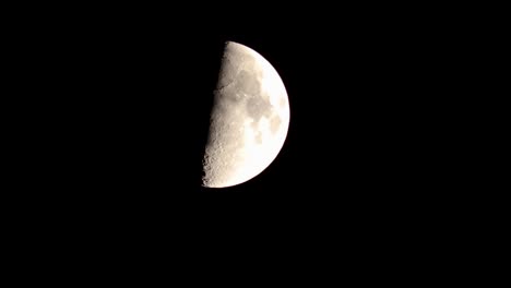 nightime closeup of quarter moon descending against a black sky