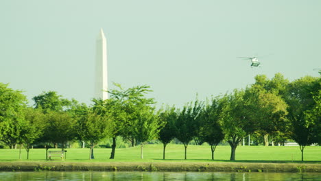 a helicopter flying next to the washington monument in washington dv from the potomac river.