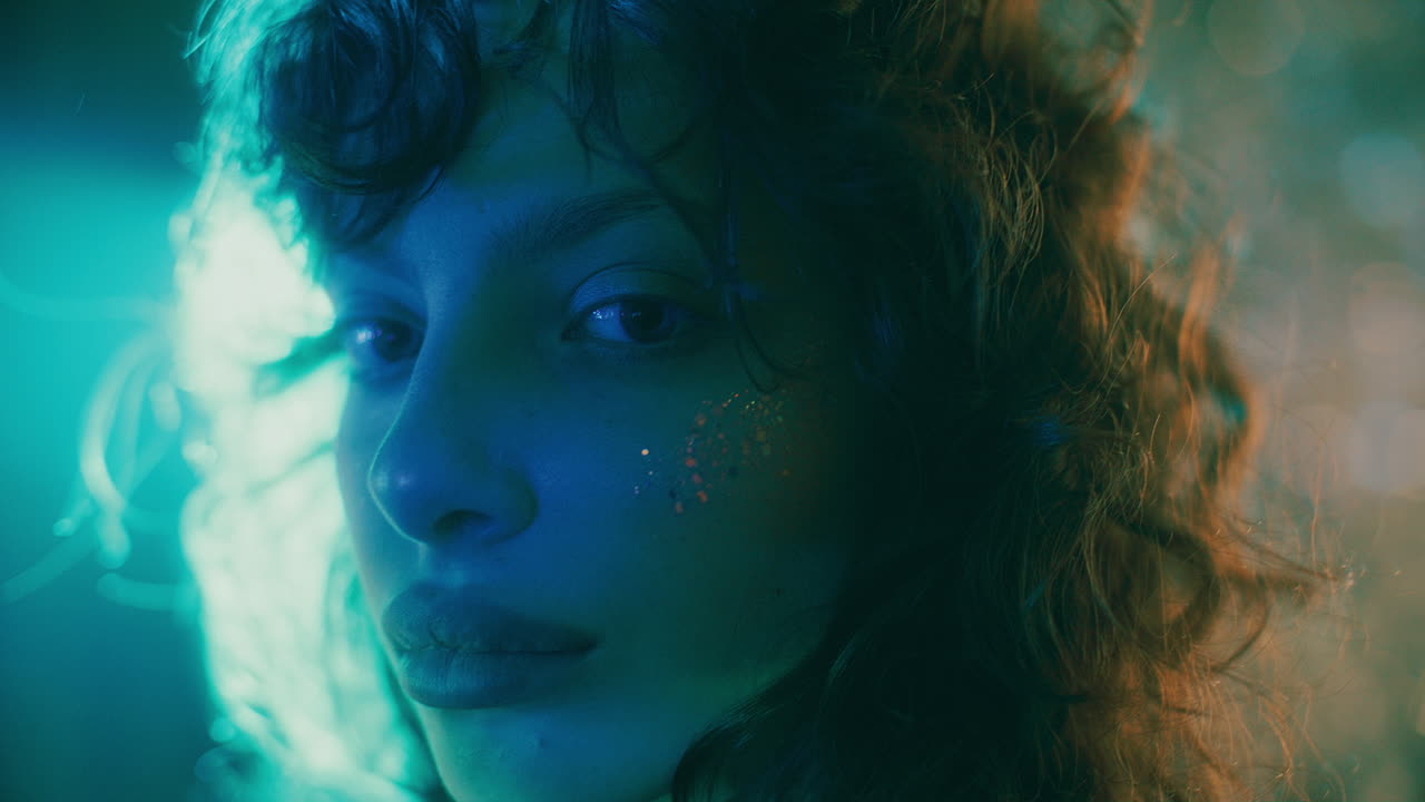 Portrait of Beautiful Girl with Glitter on Cheek in Moody Teal Lighting