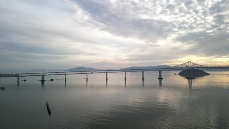 aerial drone footage at sunset captures the richmond–san rafael bridge stretching across the bay, with moving traffic and shimmering waters below.
