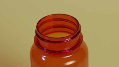 slow motion high-angle close-up of a pill bottle as a single pill falls in