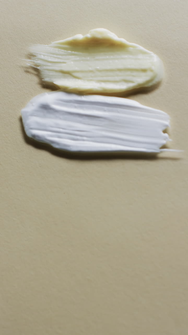 Vertical video of beauty product cream smudges with copy space on yellow background