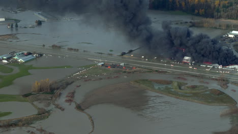 massive fire burning rv caravans with thick black smoke amidst the ravaging floods in abbotsford, bc, canada