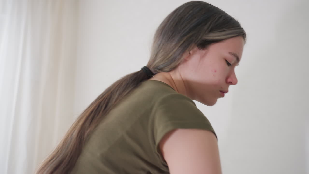 House keeper folding jeans indoors during home care, engaged in daily tidying and garment organisation, symbolising cleanliness, routine, and household lifestyle in bright living room