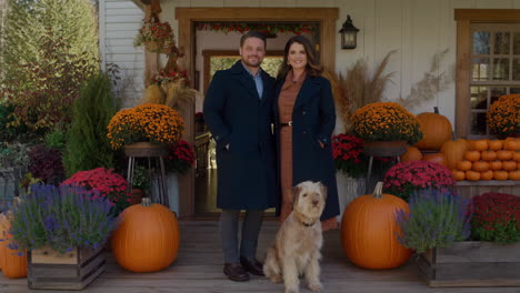 autumn front porch decorated with pumpkins, featuring a couple and their dog