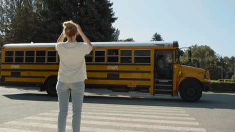 happy mom standing waving to child sitting schoolbus. woman send air-kiss to son