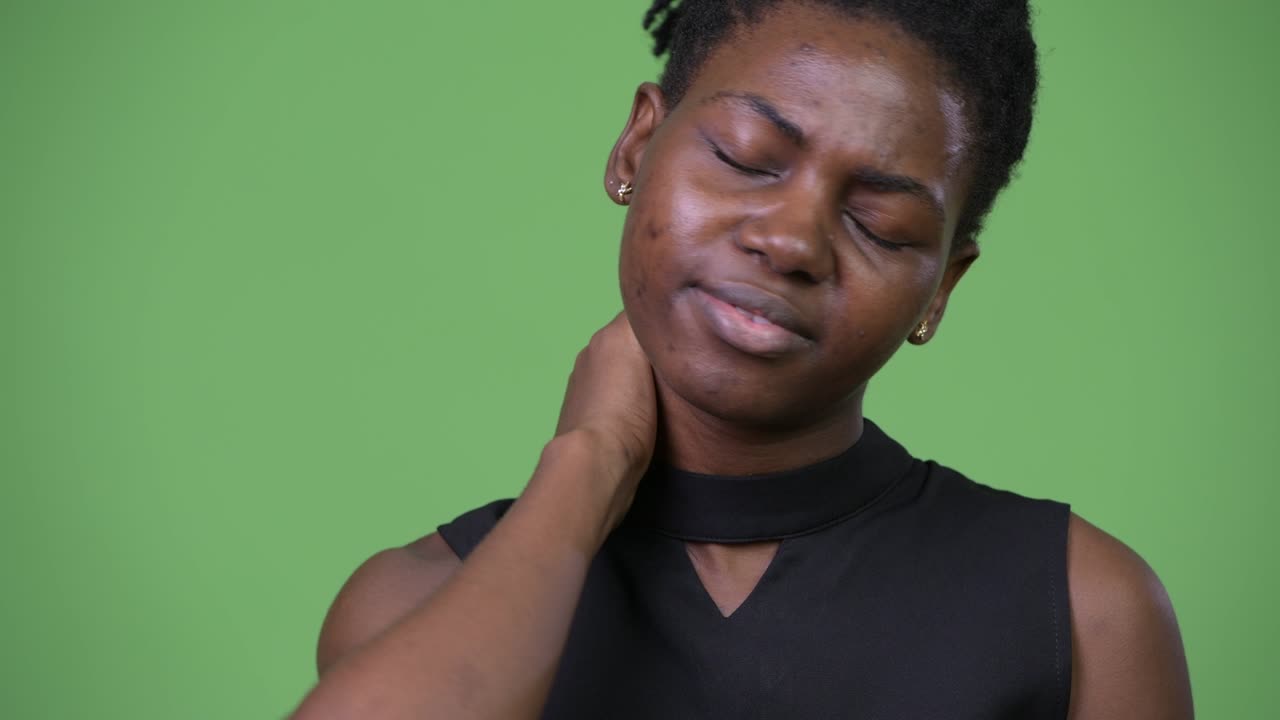 Giovane e stressata donna d'affari africana con dolore al collo