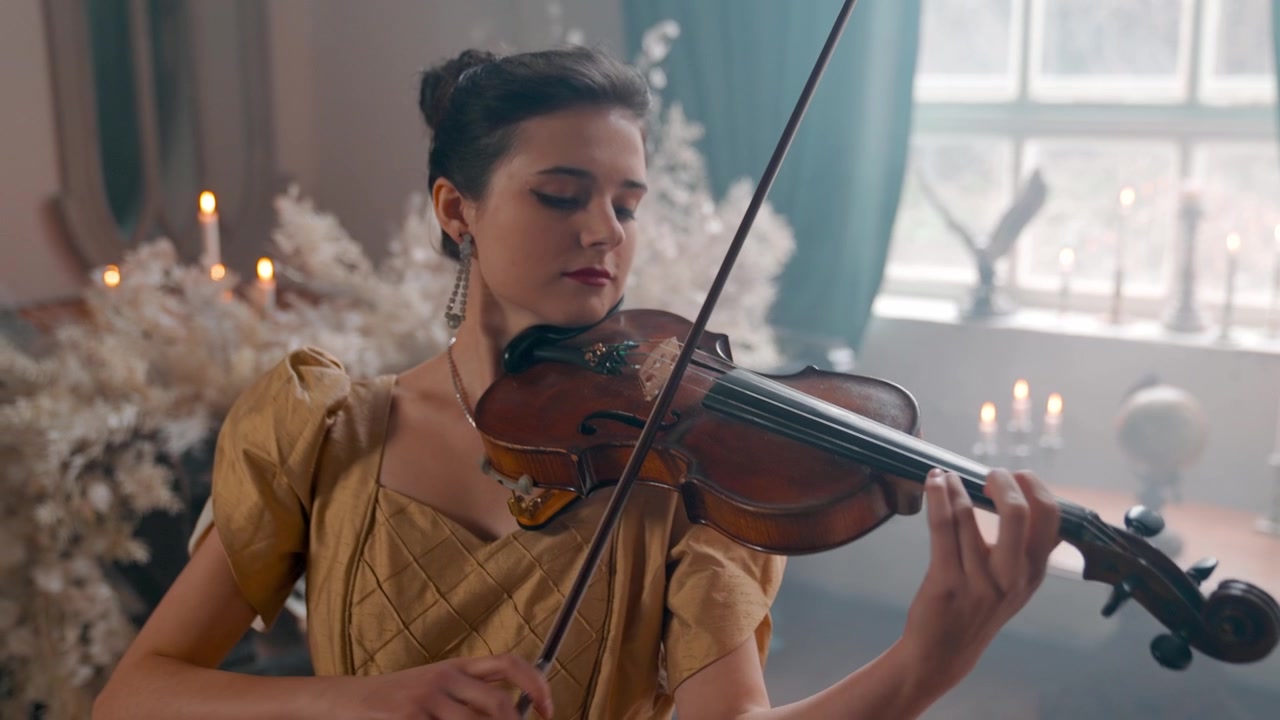 Donna elegante che suona il violino in una stanza vintage illuminata a lume di candela