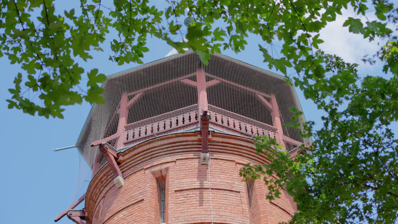 Close up shot of Aussichtsturm Paulinenwarte in T&uuml;rkenschanzpark in Vienna with green leaves in the foreground and blue sky during a sunny day at noon