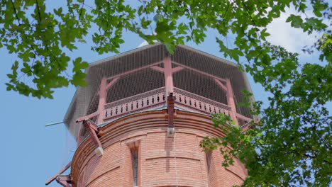 Close-up-shot-of-Aussichtsturm-Paulinenwarte-in-Türkenschanzpark-in-Vienna-with-green-leaves-in-the-foreground-and-blue-sky-during-a-sunny-day-at-noon