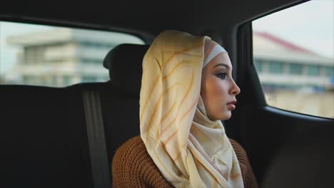 woman in hijab looking out car window