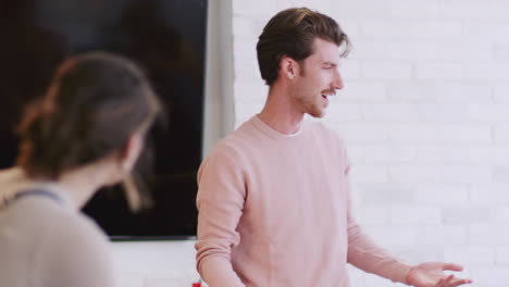 Millennial-white-male-creative-talking-to-his-colleagues-in-a-meeting-room,-close-up