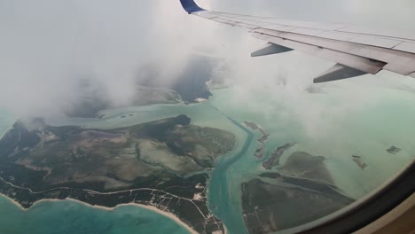 airplane wing flying above overcast island of turks and caicos in caribbean