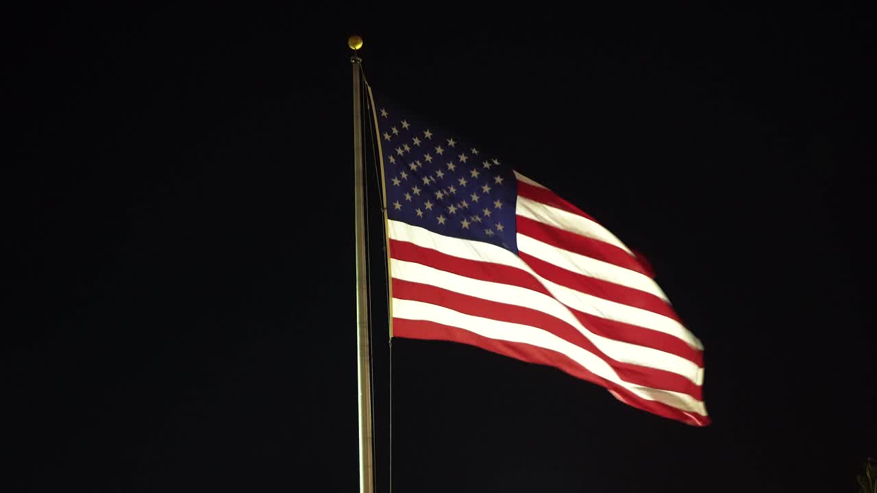 A United States flag illuminated on a cold windy night.  A close up look.