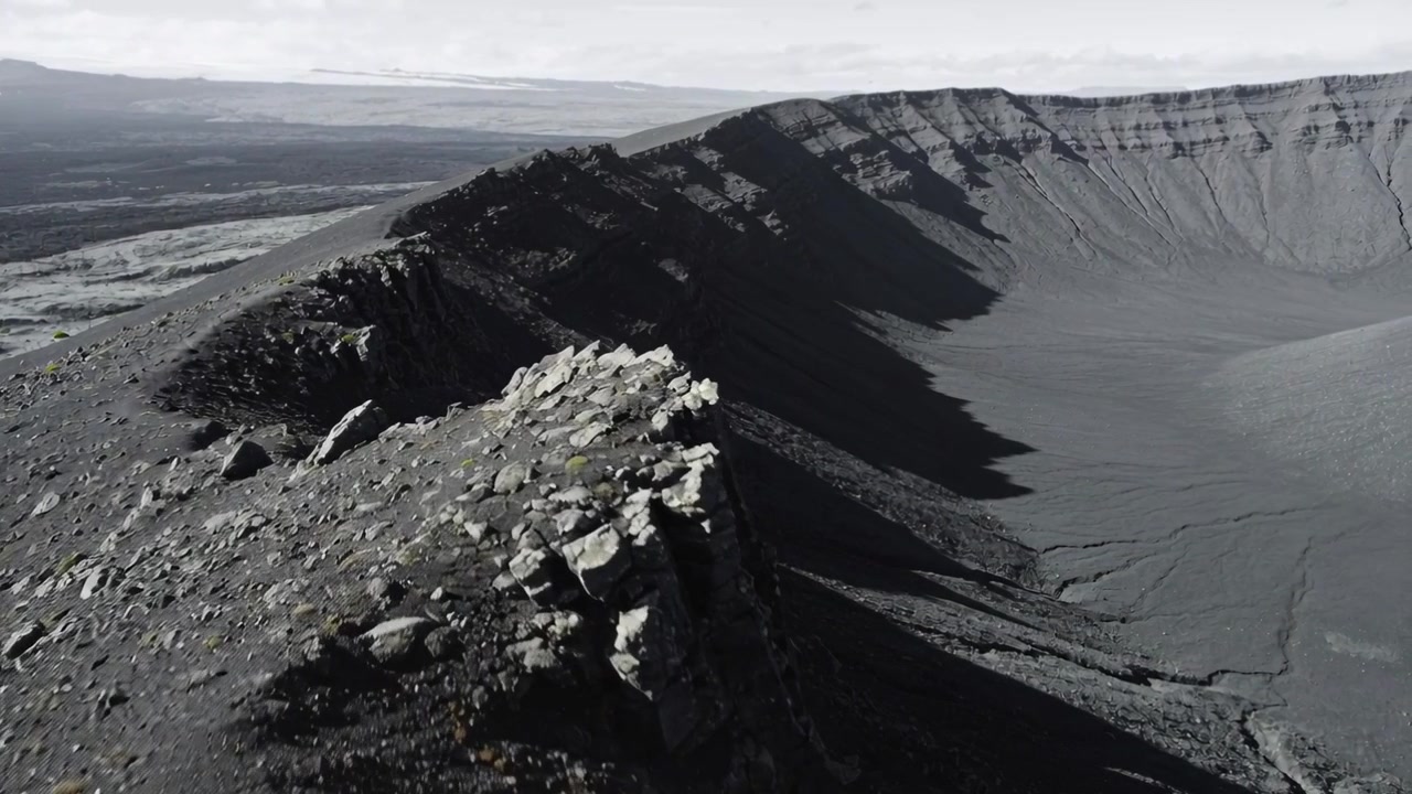 Gliding drone starting forward sweep after pilot input along crater rim, inspecting basalt blocks