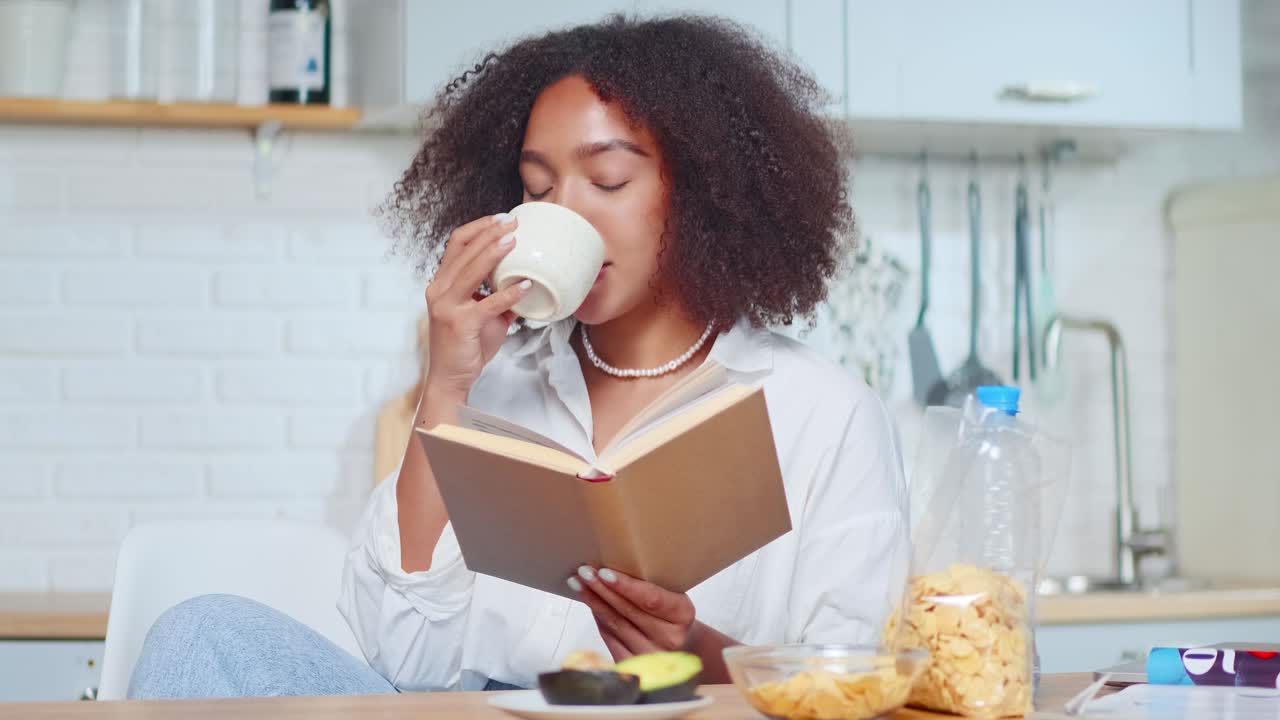 Attractive smiling african american woman reading something and drinking tea