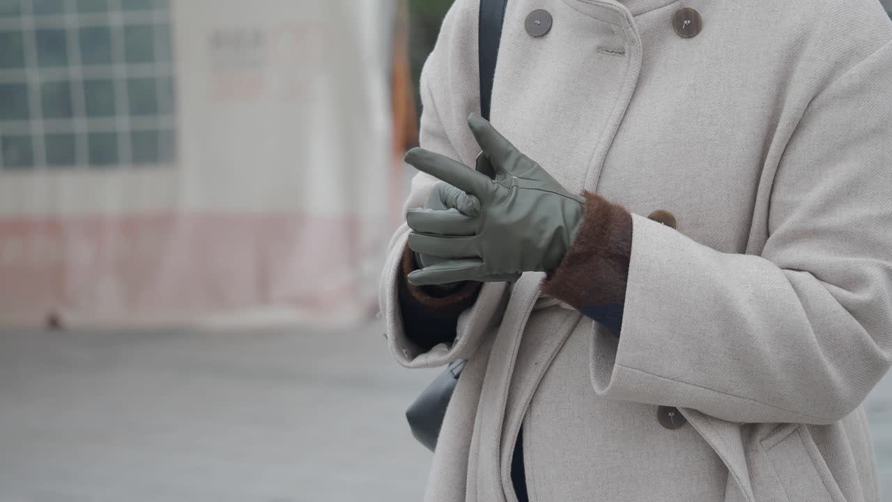 Person Adjusting Green Gloves in Winter Coat
