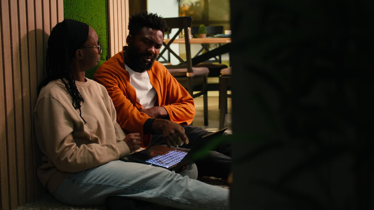 Couple enjoying weekend relaxation at home sitting comfortably with laptop