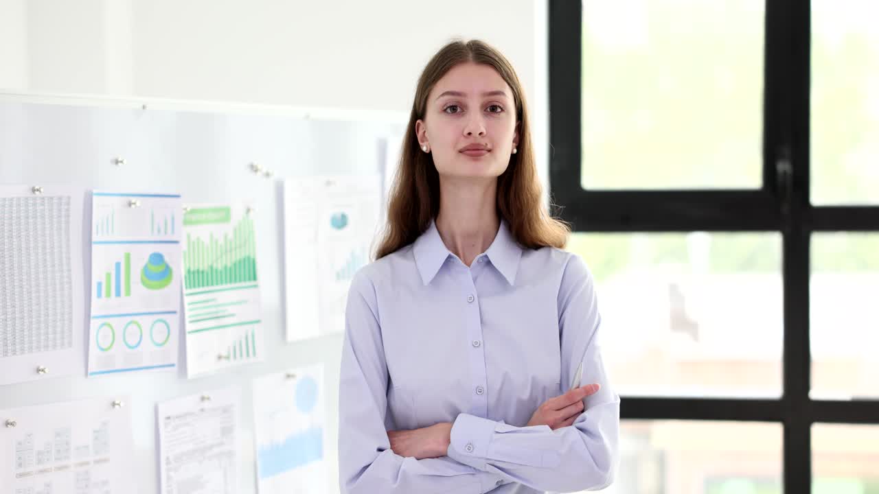 Marketer donna in ambiente aziendale che parla davanti a una lavagna bianca con grafici di analisi.