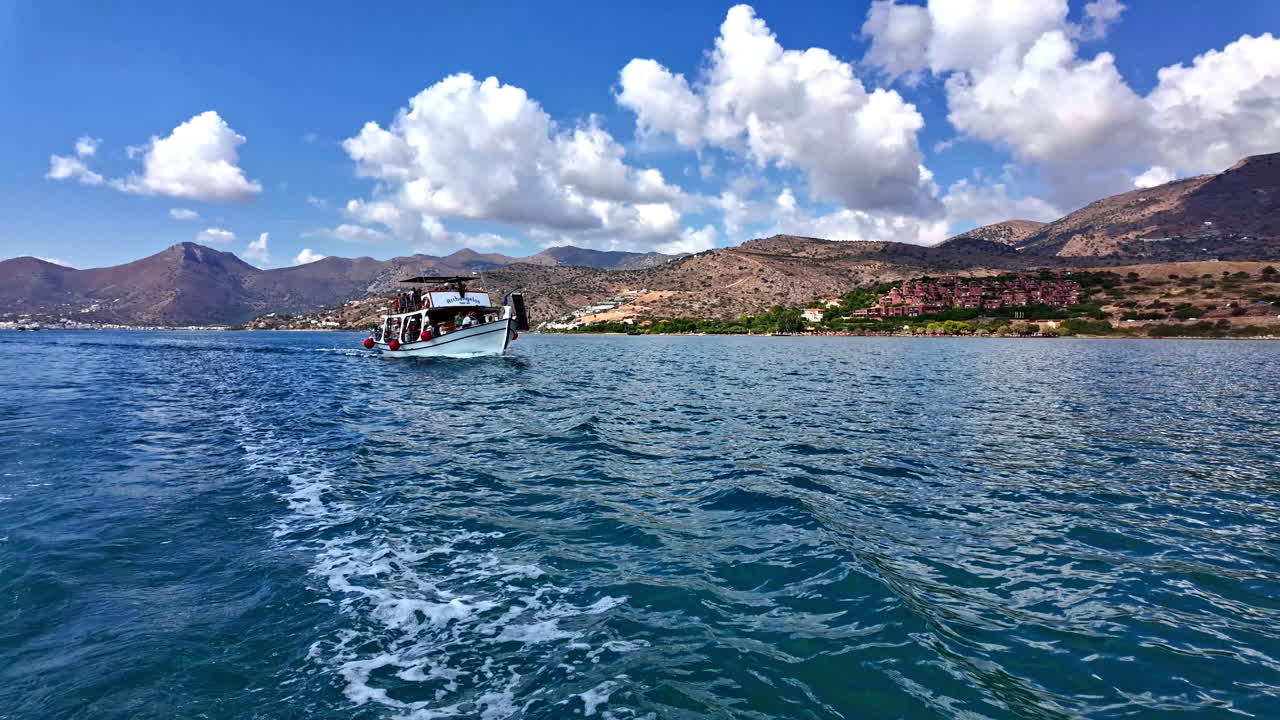 그리스 시티아 근처의 파란 물을 가로질러 항해하는 배, 밝은 하늘 아래의 경치 좋은 산의 배경