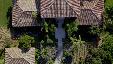 aerial top down shot of person entering luxury villa during sunny day with tropical large garden